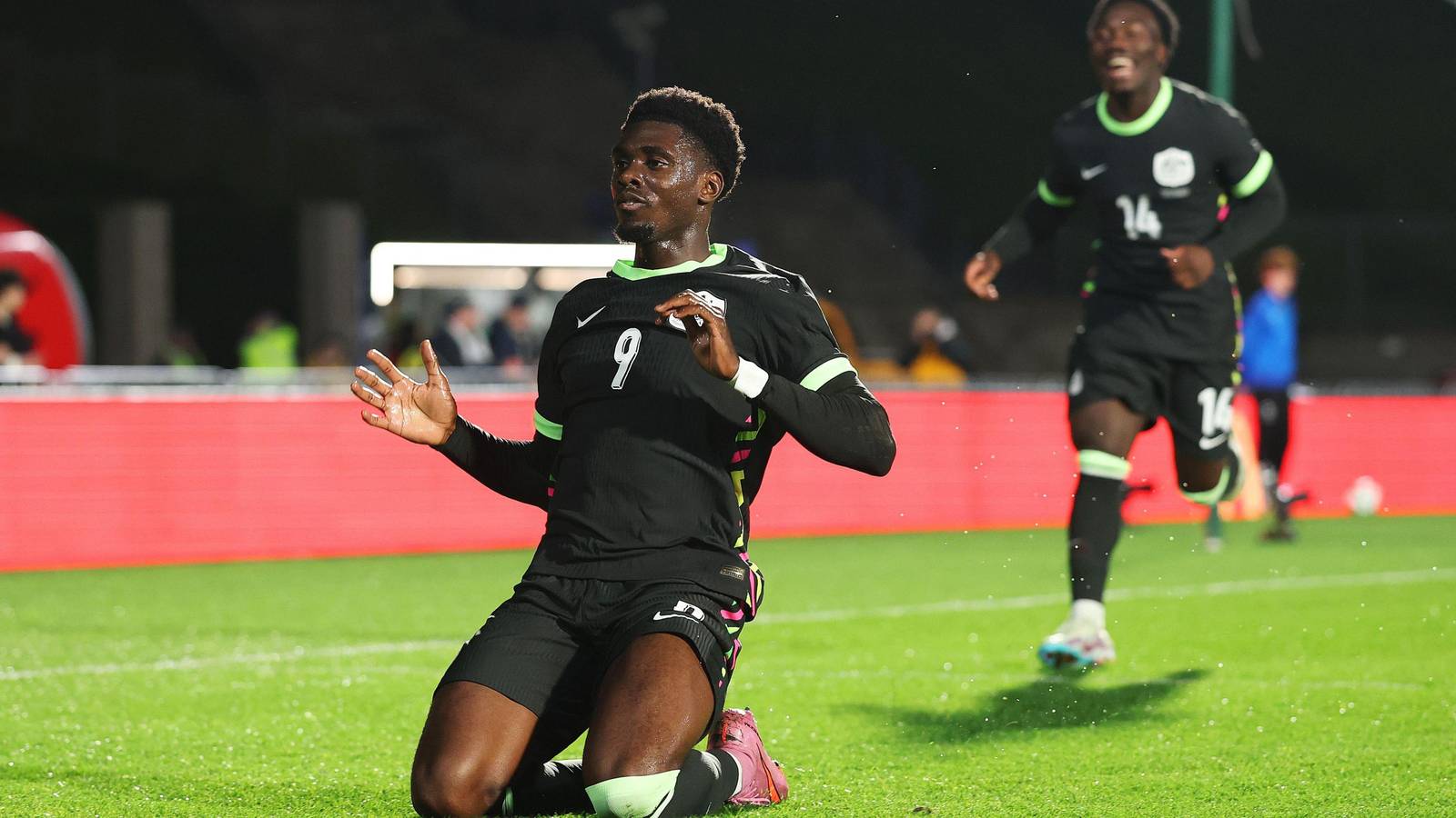 Mohamed Toure kneeling on the pitch celebrating a goal in a black jersey