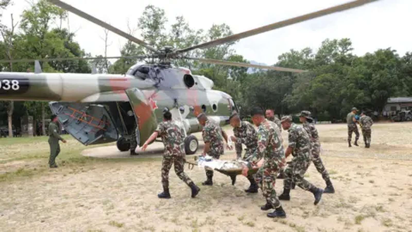 Nepalese military personnel carrying a stretcher toward a rescue helicopter during disaster relief o