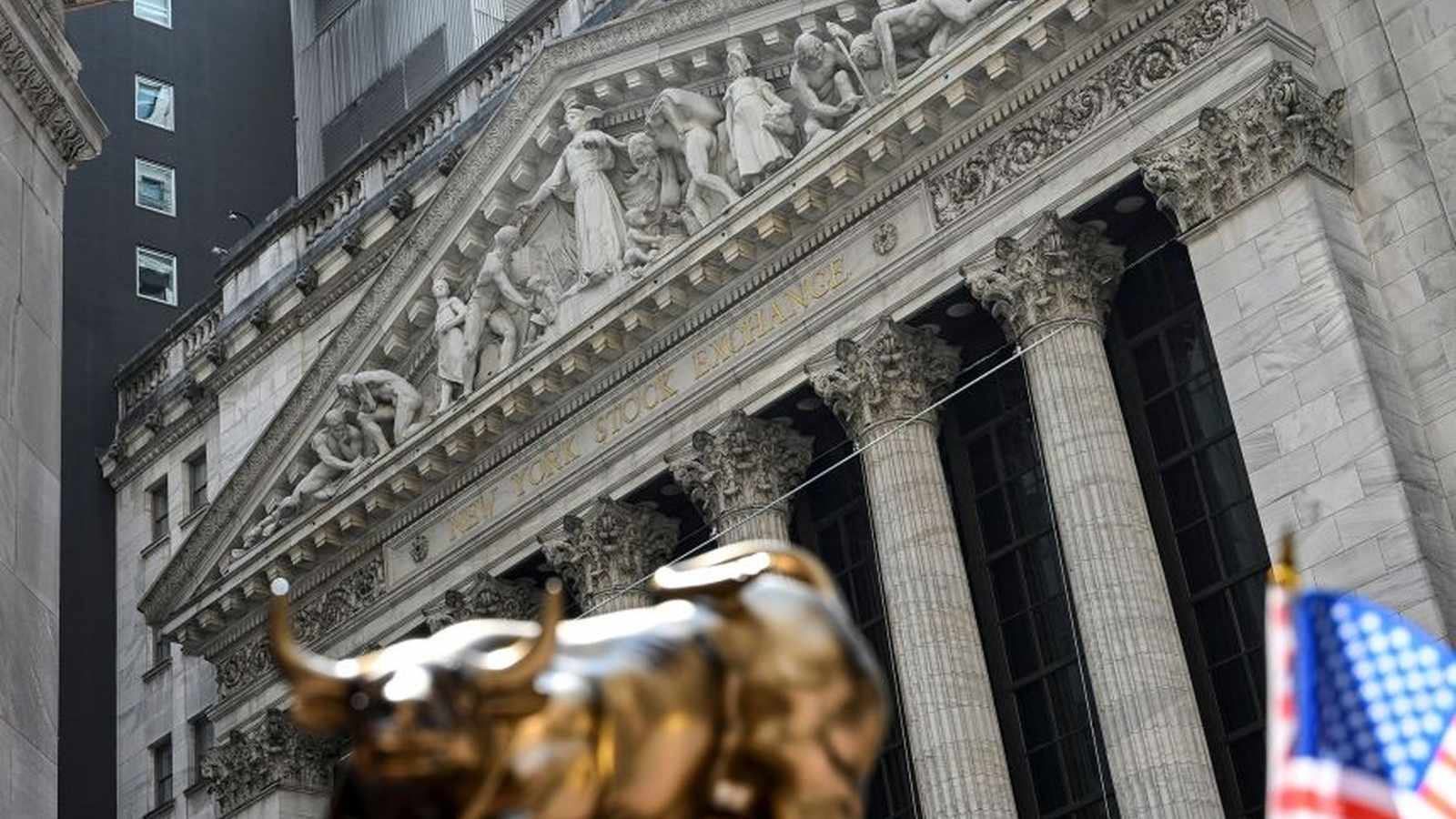 The neoclassical facade of the New York Stock Exchange building with a bull statue