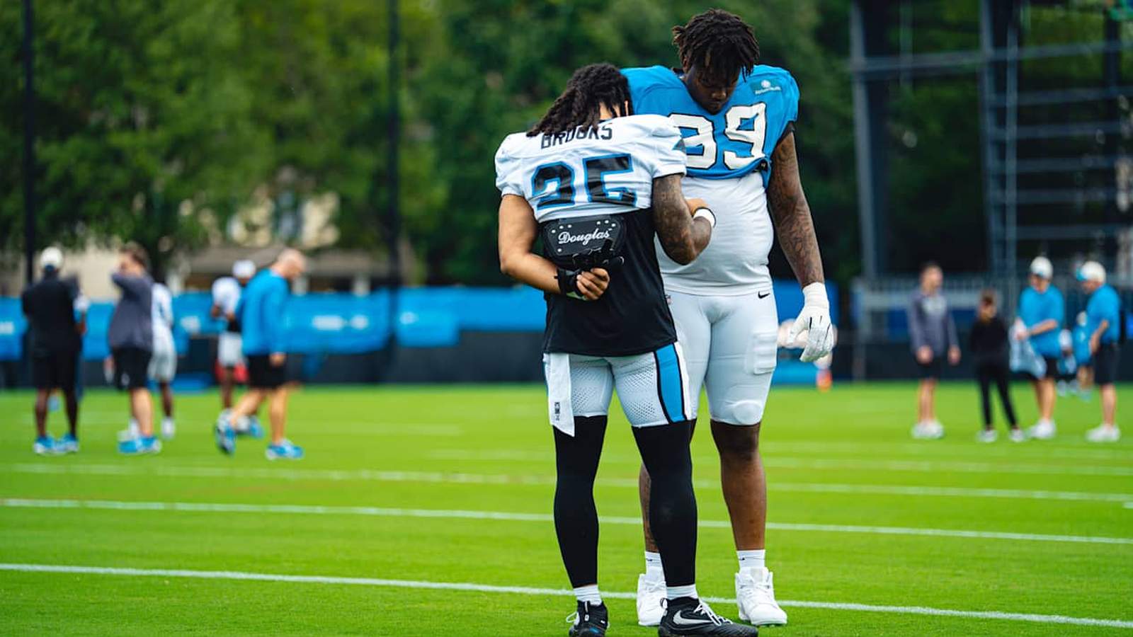 Two Carolina Panthers football players standing together on the field during a practice session
