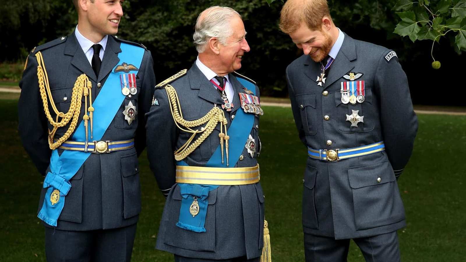 Prince William, King Charles, and Prince Harry standing together in formal military uniforms outdoor