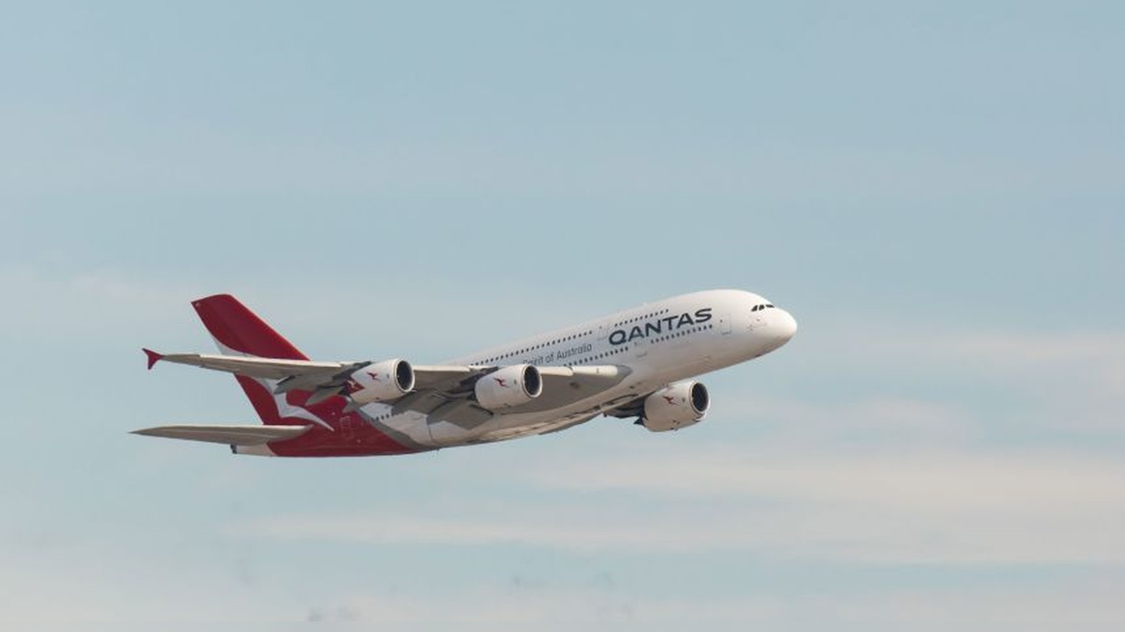 A Qantas A380 passenger jet flying through a clear blue sky during daytime