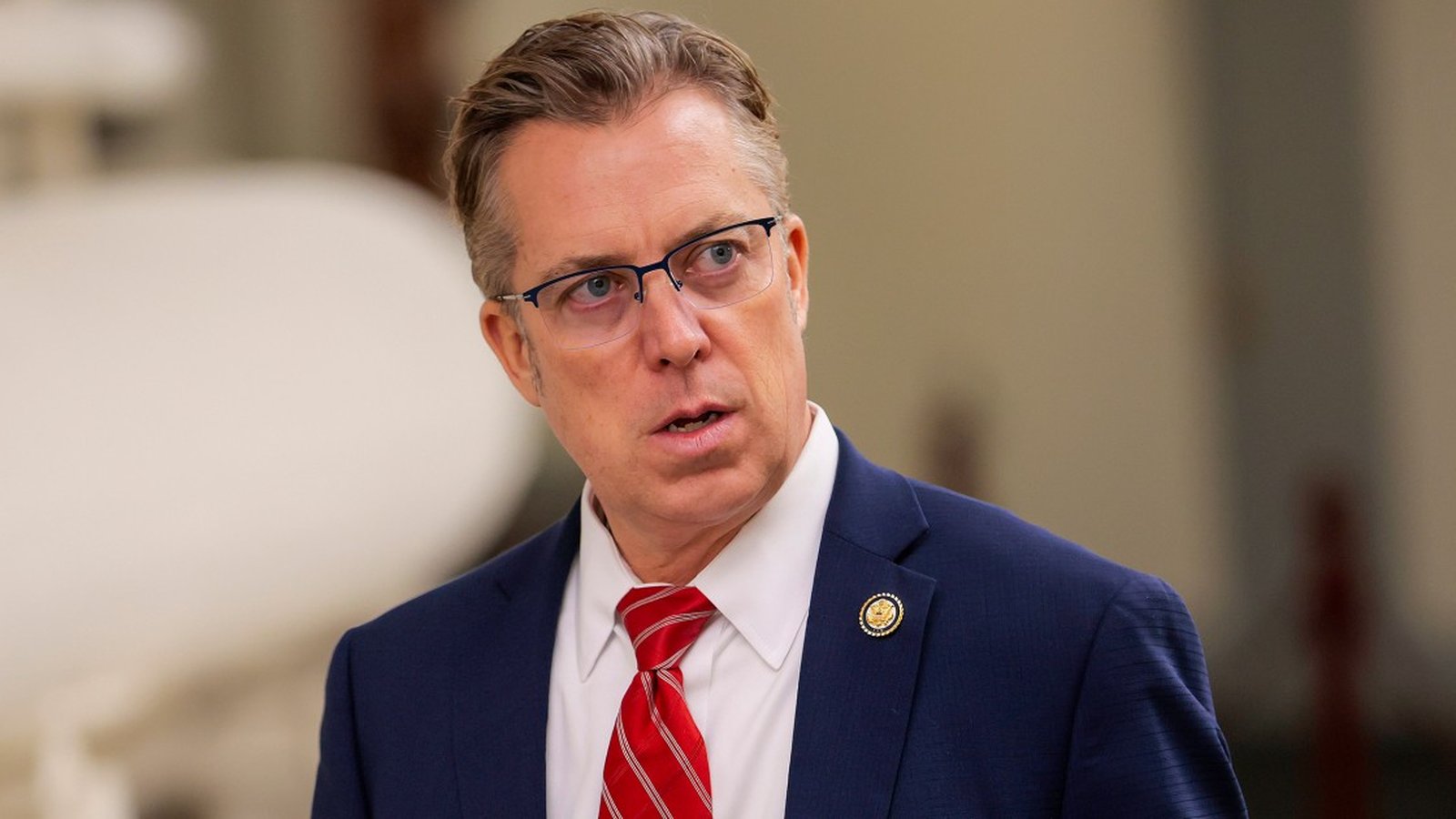 Representative Andy Ogles wearing a blue suit and red tie looking forward
