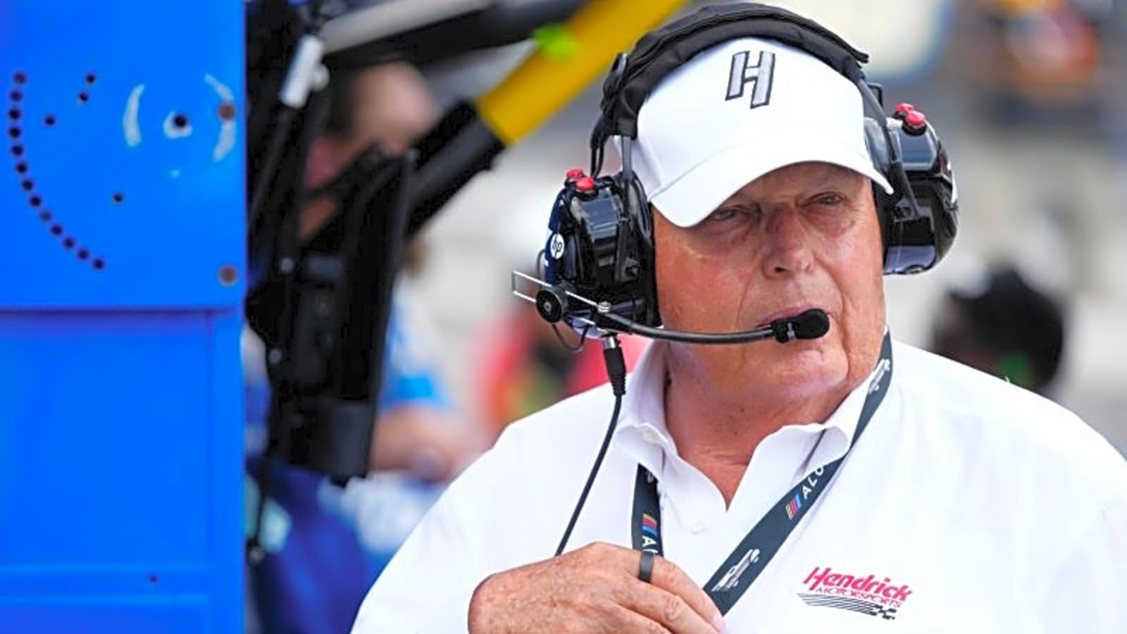 Rick Hendrick wearing a white Hendrick Motorsports shirt and headset at the track