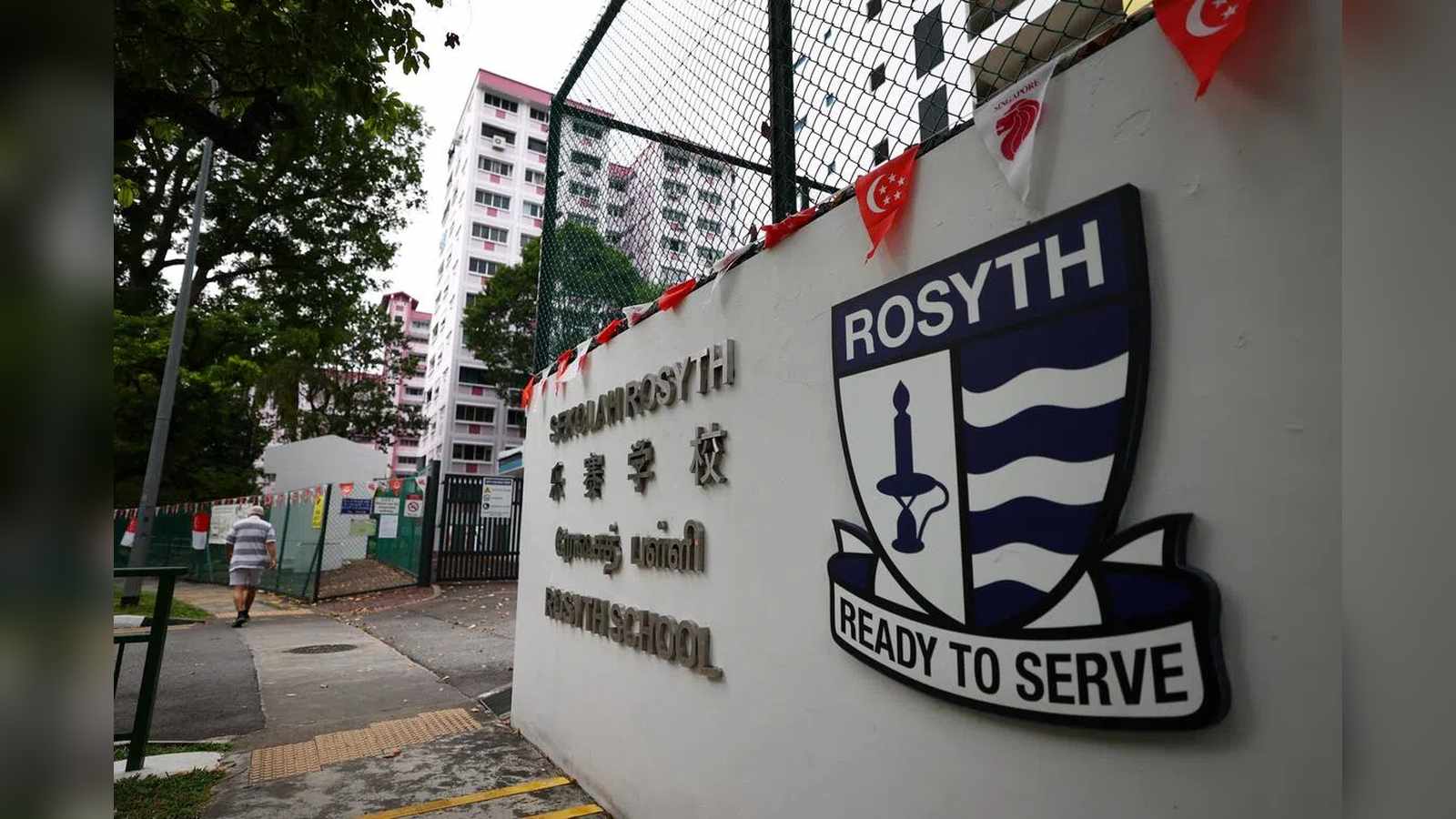 The entrance wall and crest of Rosyth School in Singapore with residential buildings behind