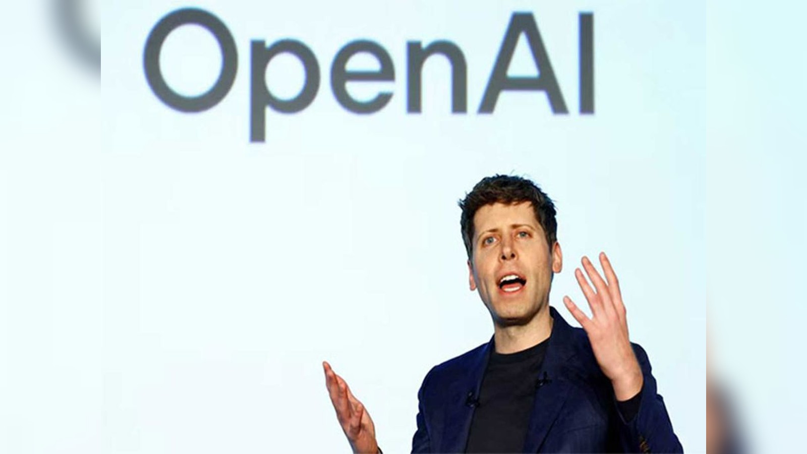 Sam Altman speaking on stage in front of a large OpenAI company logo