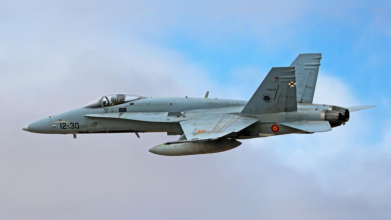 A Spanish Air Force F-18 fighter jet flying through a cloudy sky