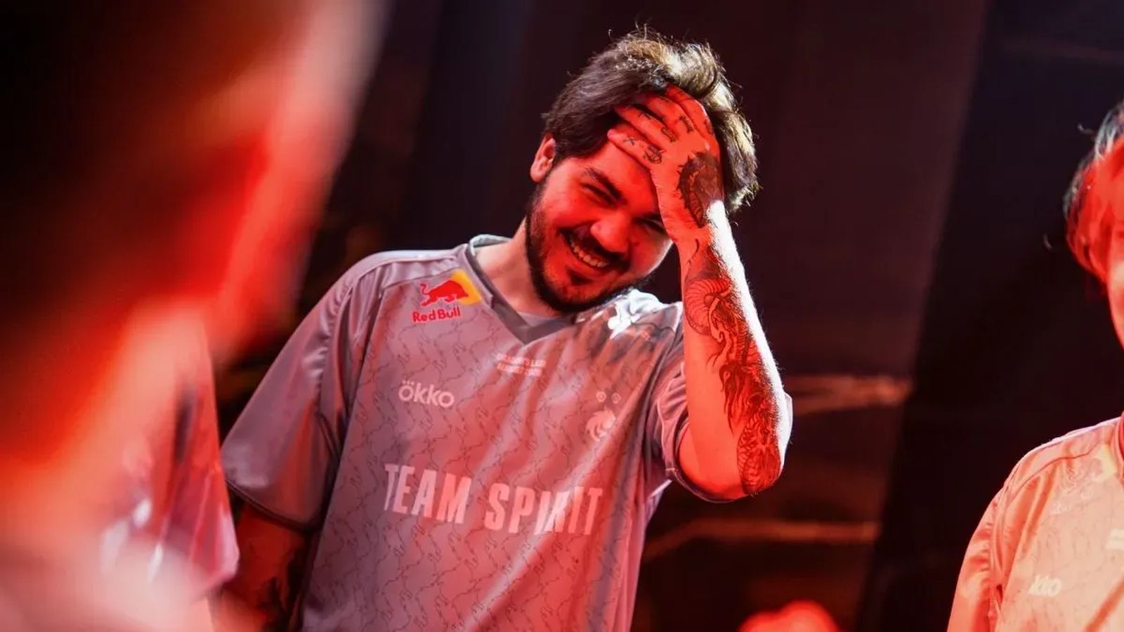 A smiling Team Spirit esports player with tattoos celebrating after a tournament match win