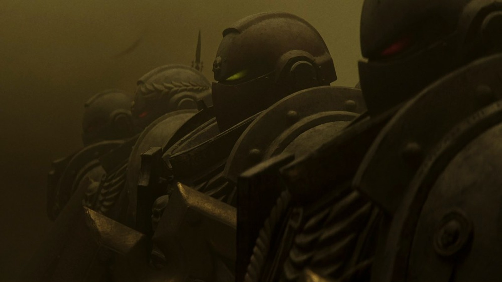 A line of armored Space Marines in helmets standing in a dark, dusty environment