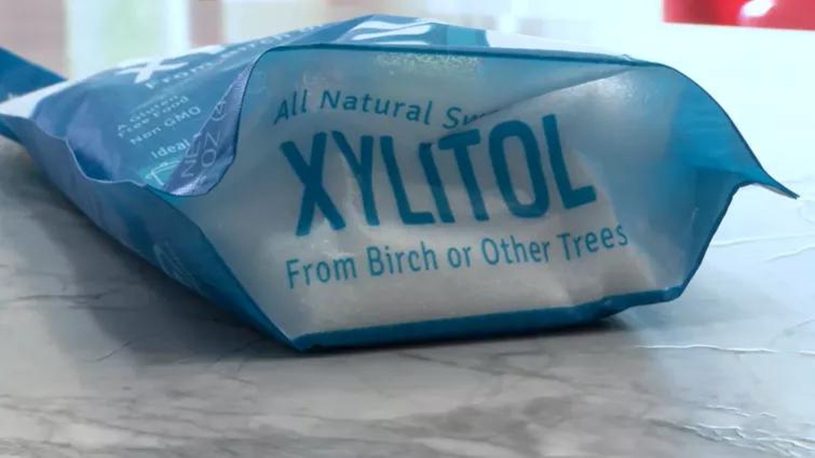 A blue bag of xylitol sweetener sitting on a marble countertop surface