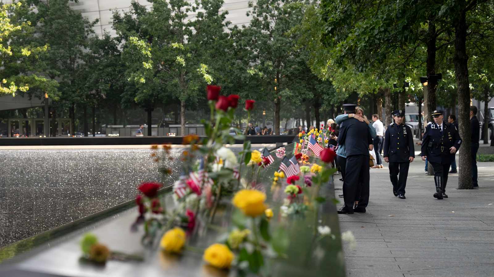Police officers walking past flowers placed at the 911 memorial reflecting pool site