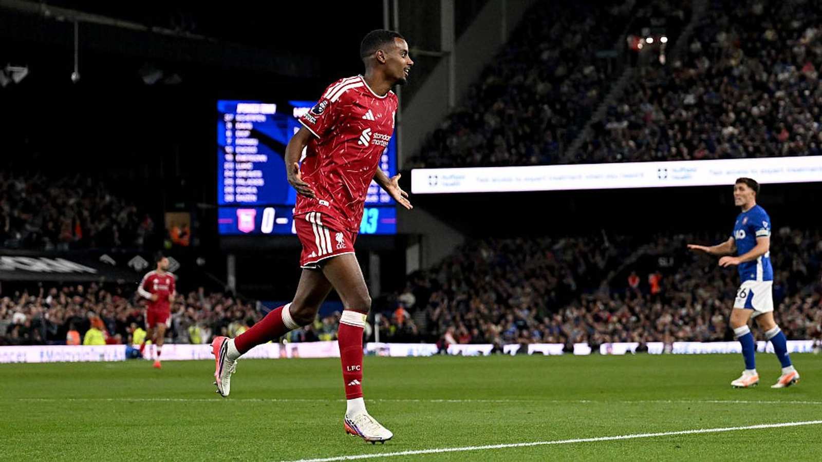 Alexander Isak running in celebration wearing a red Liverpool kit on the pitch