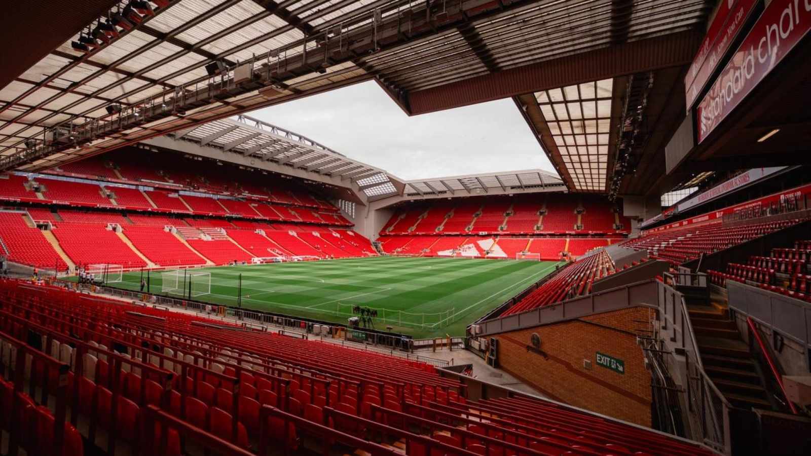 Wide angle view of the empty Anfield stadium pitch and red seating stands