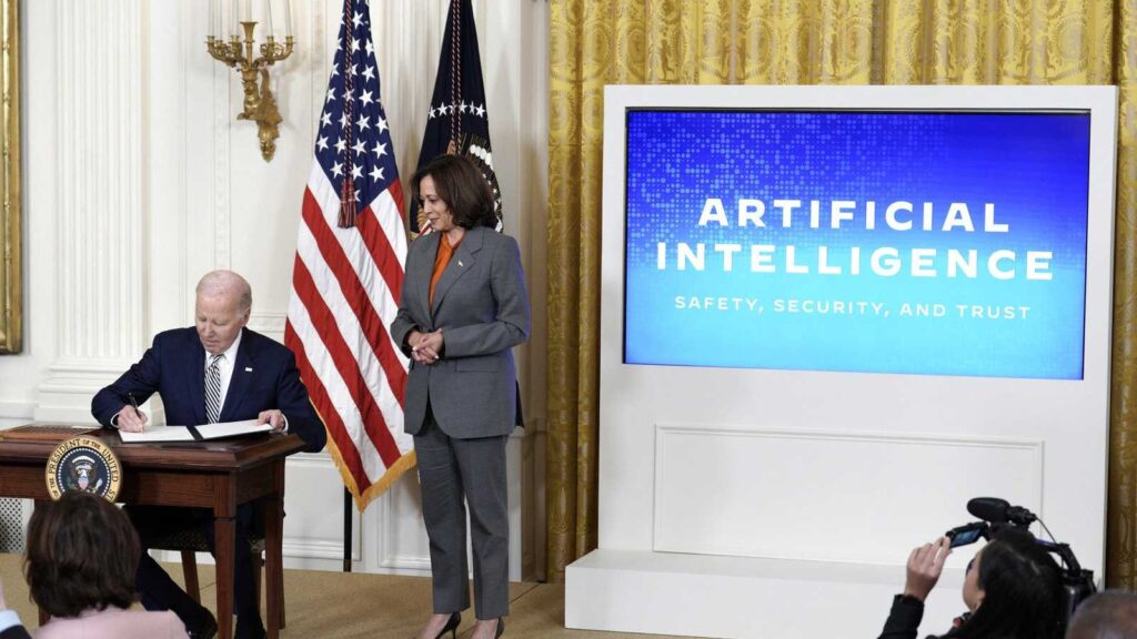 President Joe Biden signing documents with Vice President Kamala Harris standing nearby beside a dig