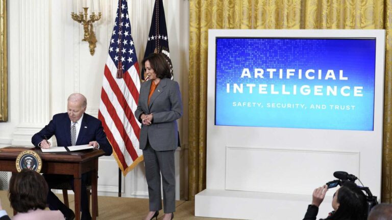 President Joe Biden signing documents with Vice President Kamala Harris standing nearby beside a dig