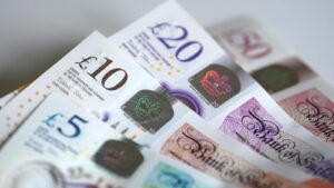 A close-up view of stacked British pound banknotes including five, ten, and twenty pound notes