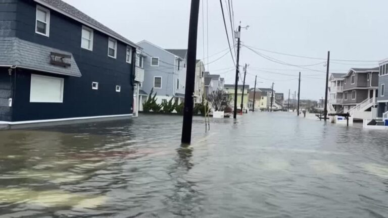 A flooded residential street with water covering the road during a coastal storm event