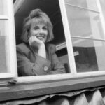 Black and white portrait of broadcaster Dame Esther Rantzen leaning out of a window