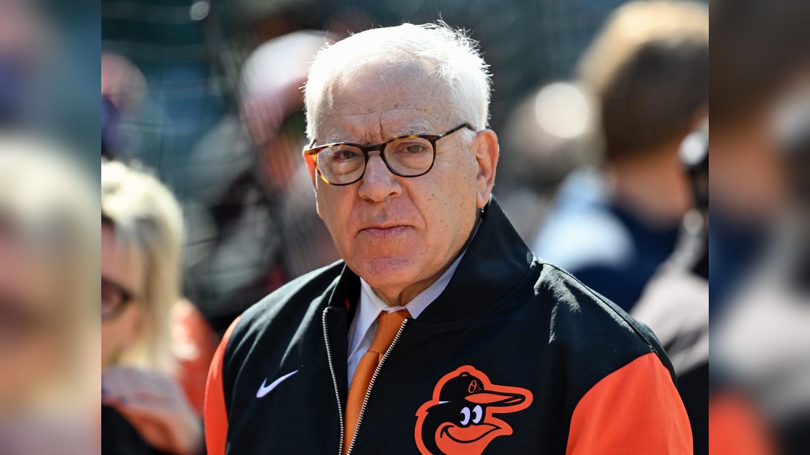 David Rubenstein wearing a black and orange Baltimore Orioles jacket at a stadium