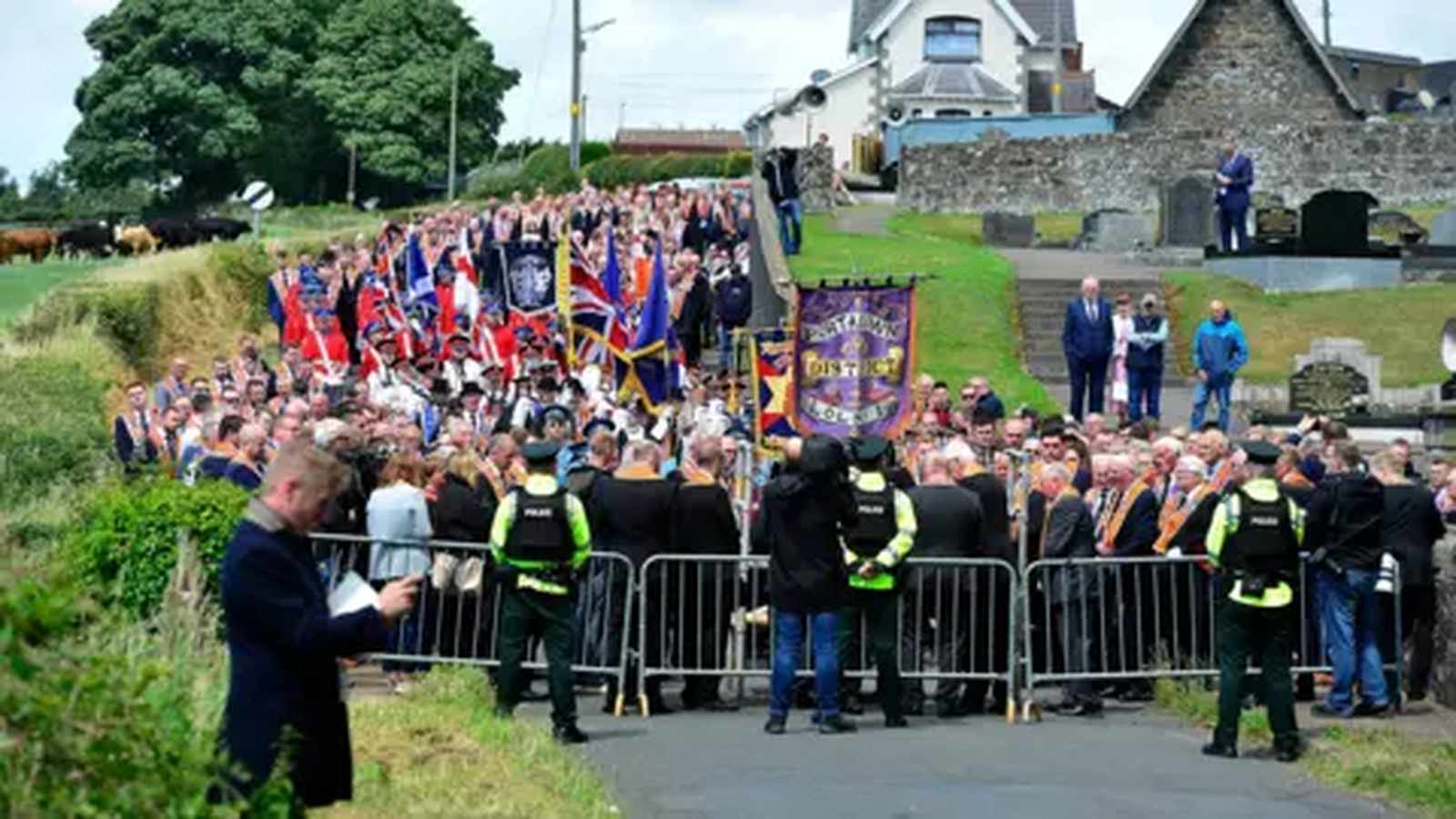 Large crowd of marchers and police officers standing at a parade in Northern Ireland