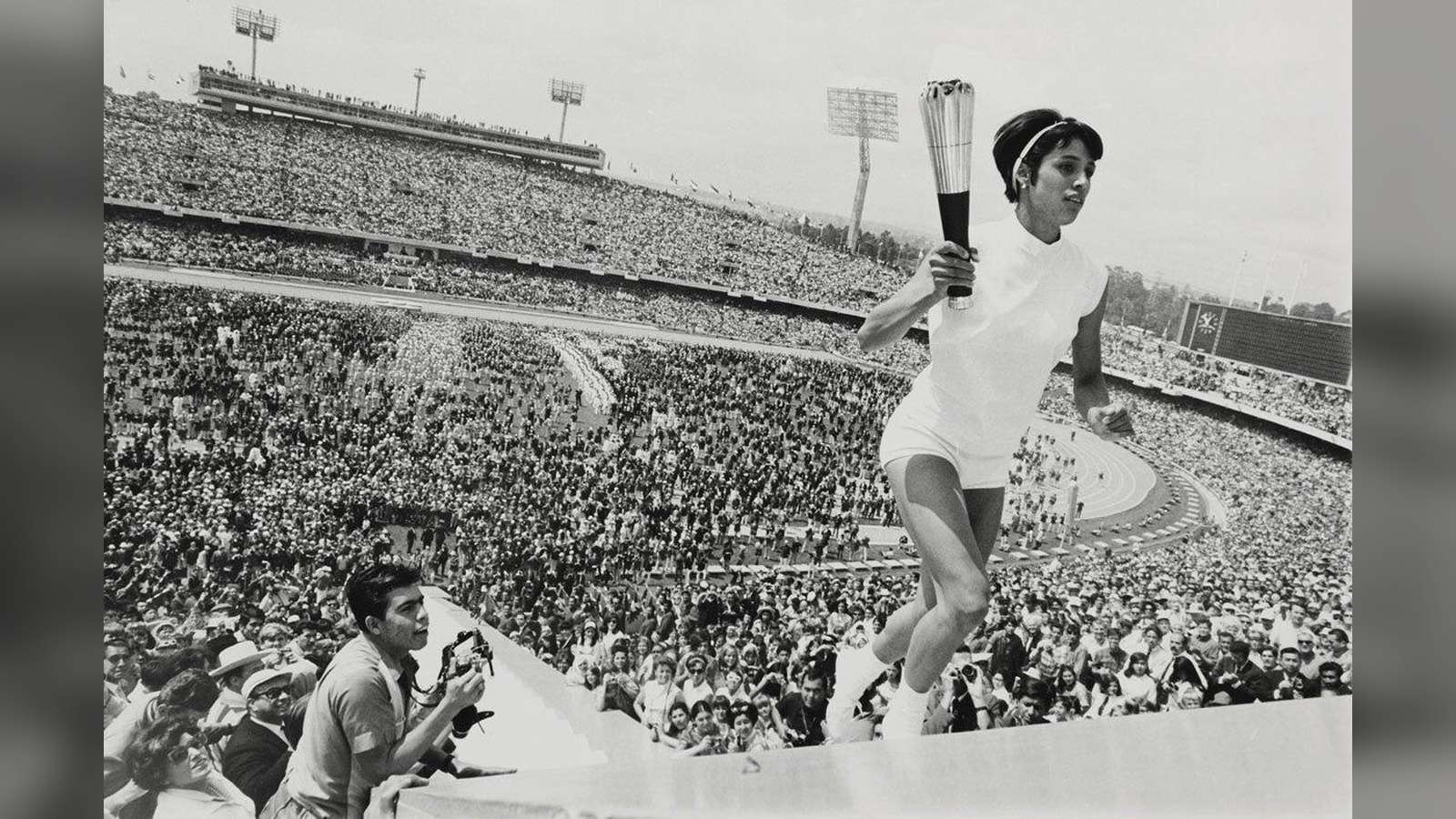 Black and white photograph of Enriqueta Basilio holding the Olympic torch high at the top of Mexico