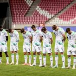 Irish soccer players in white and green uniforms lined up on the pitch