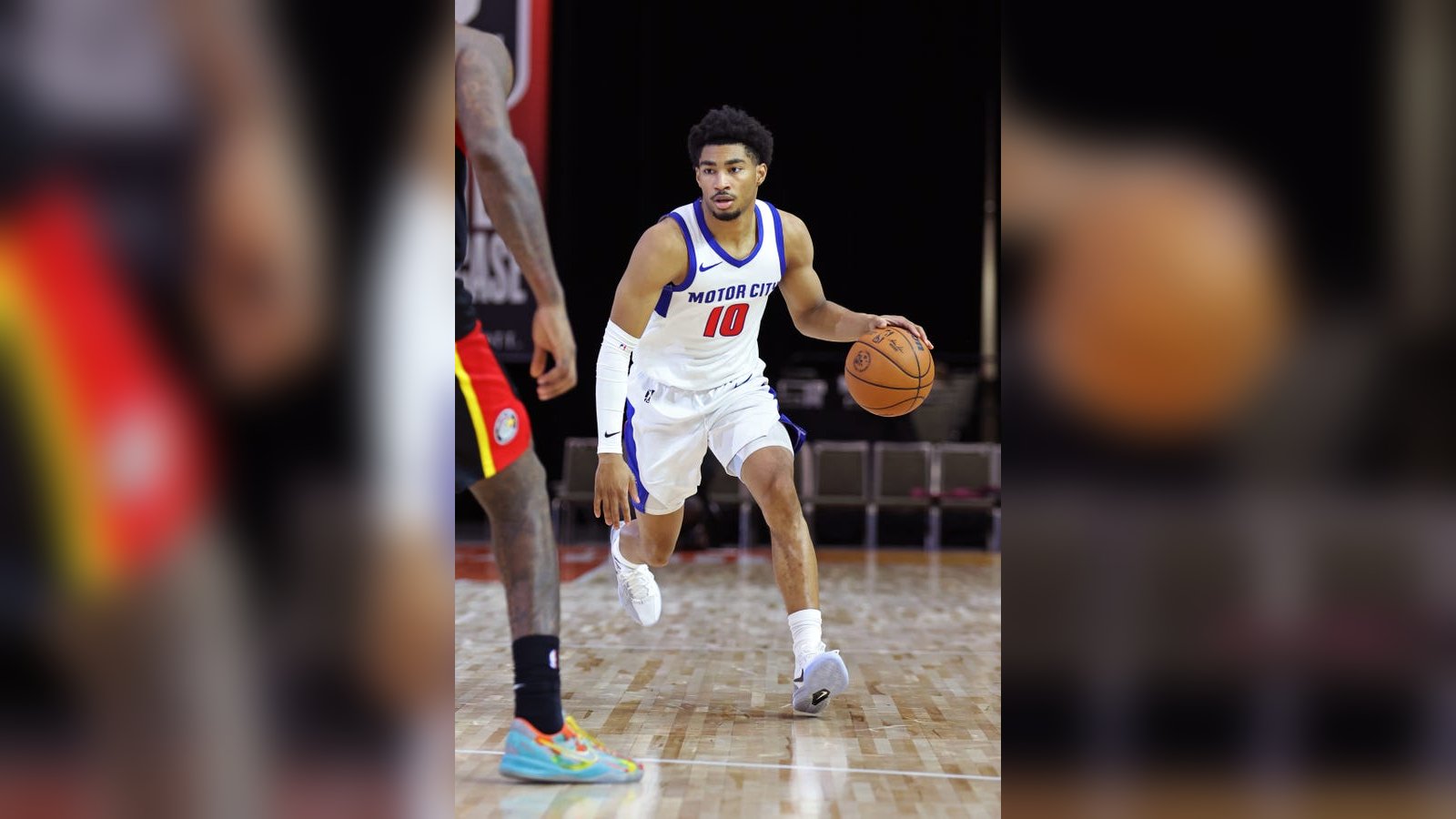 Jaden Akins wearing a white Motor City basketball jersey dribbling the ball on court