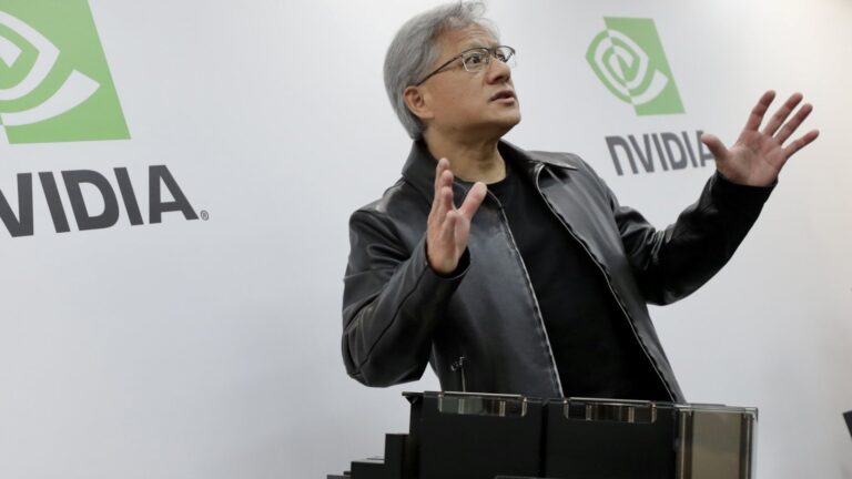 Nvidia CEO Jensen Huang gesturing in front of company branding during a presentation