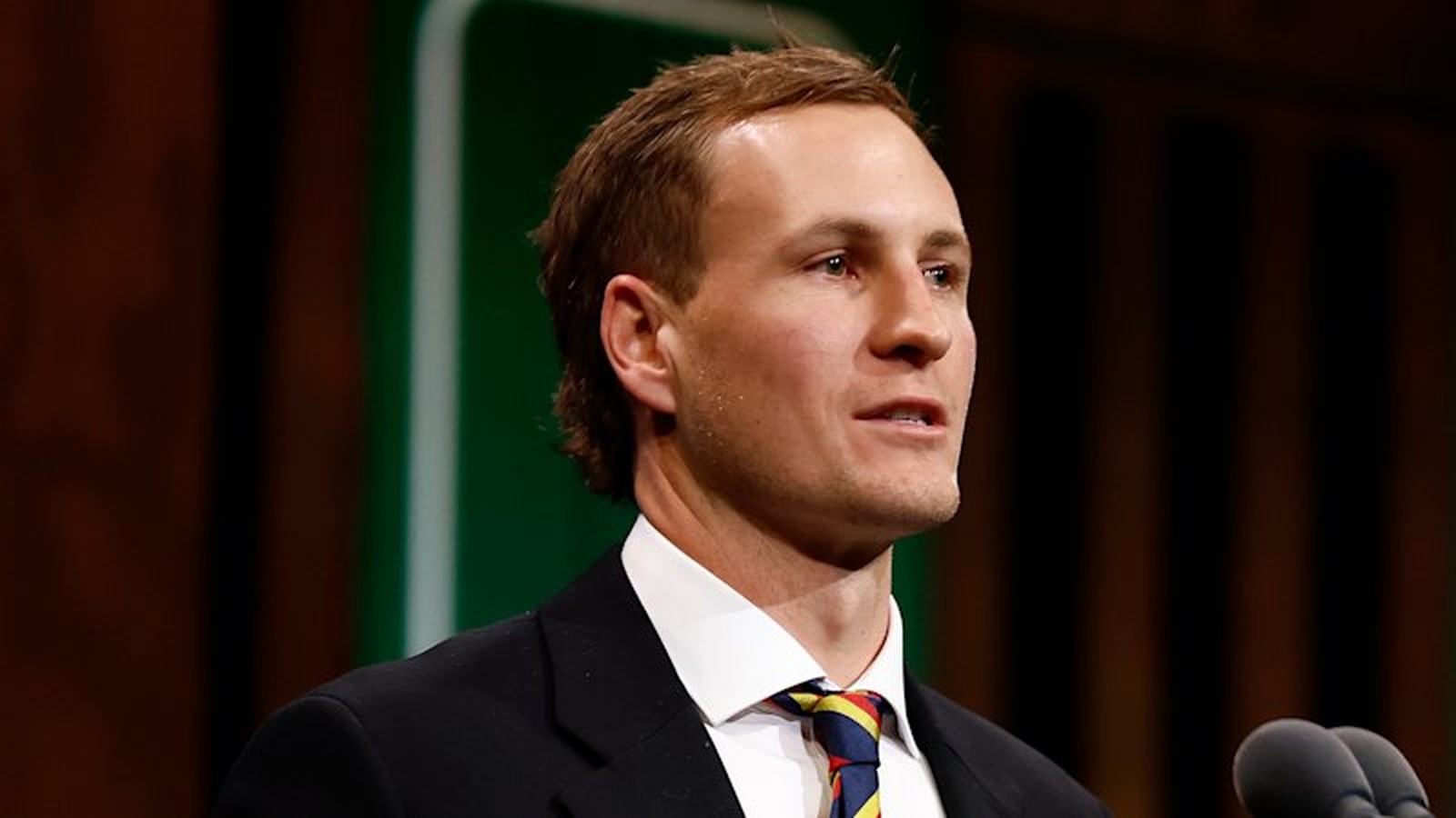 Adelaide Crows captain Jordan Dawson speaking at a formal event in a suit