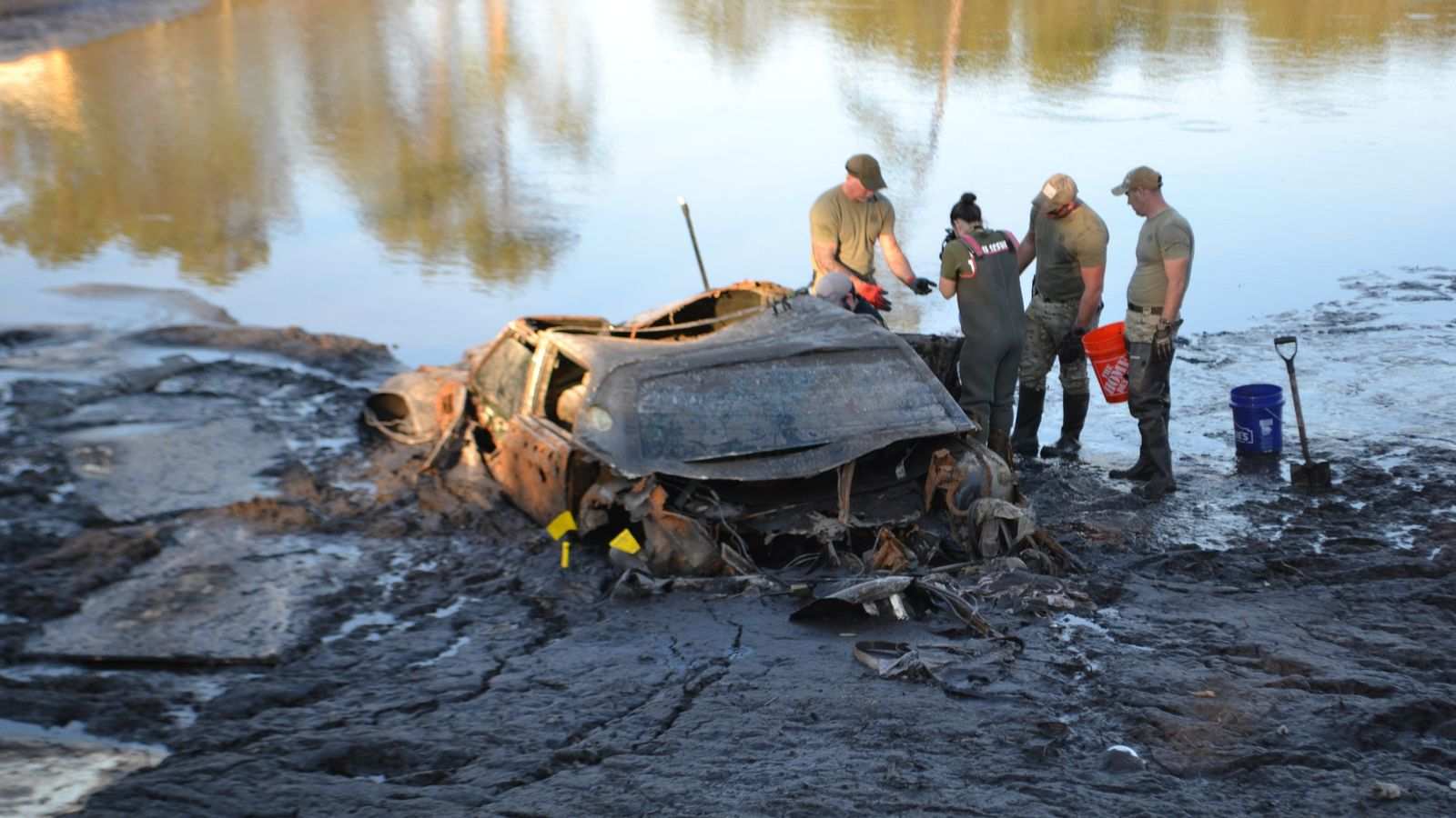 Search and rescue team members standing near a submerged vehicle recovered from Lake Nelson
