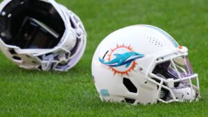 Two Miami Dolphins football helmets resting on the green grass of a stadium field