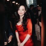 Actress Mikey Madison smiling in a red dress at a public event