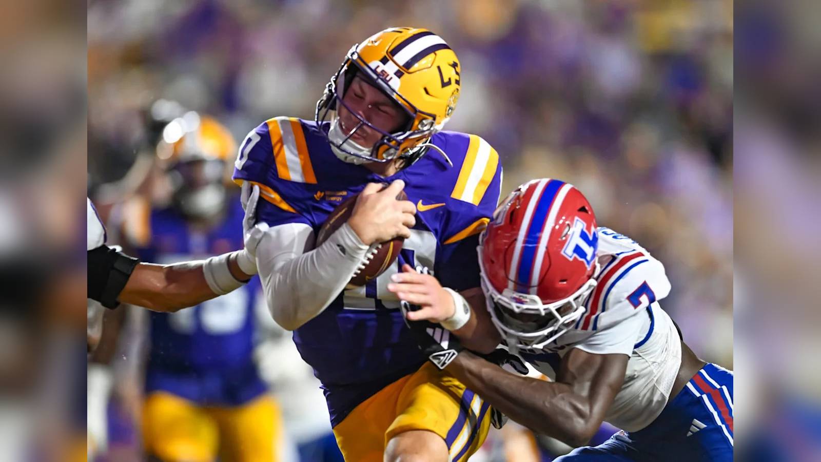 LSU quarterback Sam Leavitt carrying the football while being tackled by an opposing player