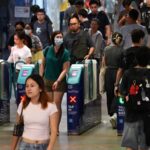 Commuters walking through automated fare gates at a crowded Singapore Mass Rapid Transit station