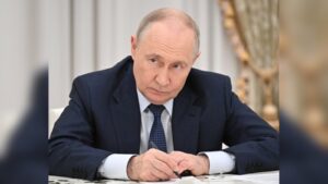 Russian President Vladimir Putin sitting at a desk and writing on documents