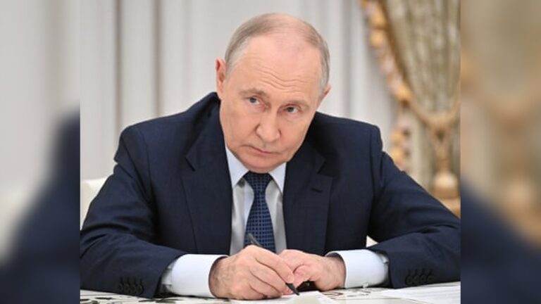 Russian President Vladimir Putin sitting at a desk and writing on documents