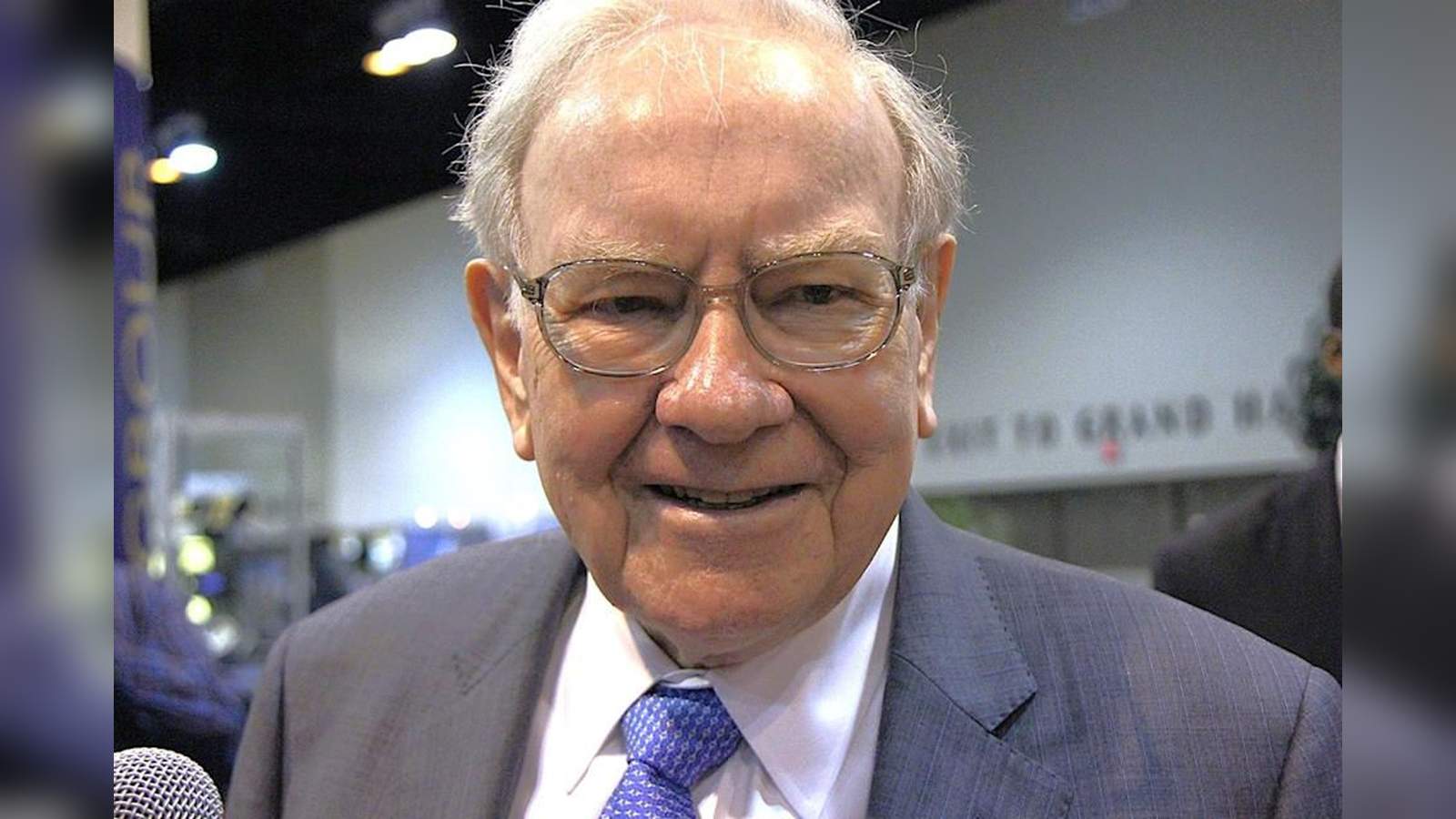 Close up portrait of Warren Buffett wearing glasses and a blue patterned tie