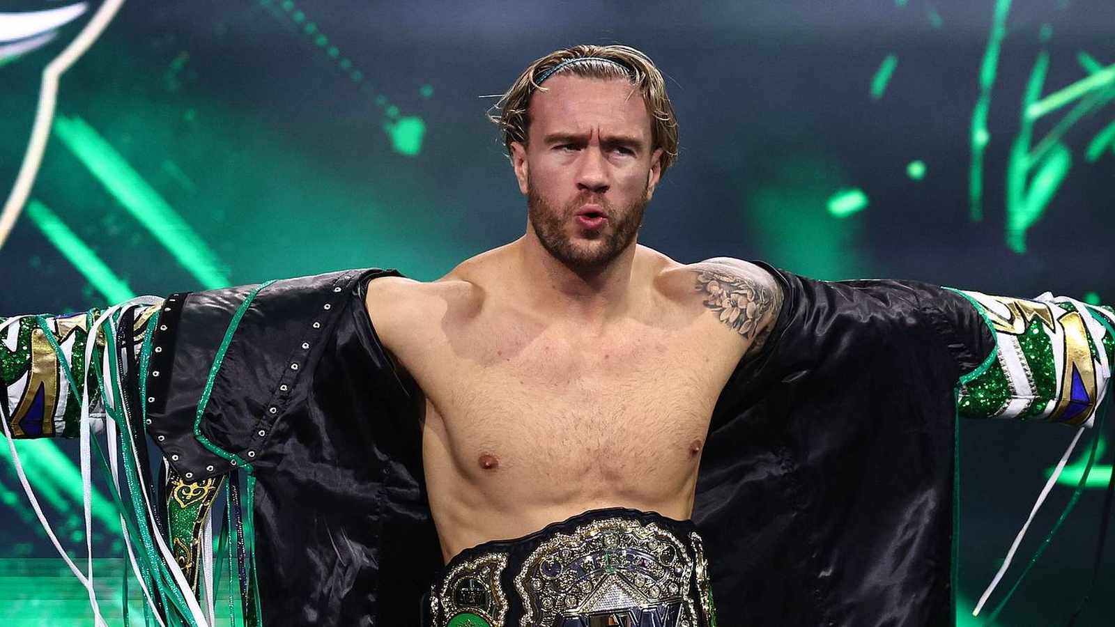 Will Ospreay standing in the ring wearing his championship belt at AEW All Out