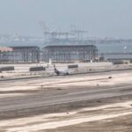Airplanes on the tarmac at Aden International Airport with industrial cranes in the background