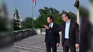Serbian President Aleksandar Vucic and Jared Kushner standing on a balcony pointing towards a buildi
