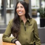 Portrait of Xbox leader Asha Sharma smiling in an office setting wearing an olive green shirt