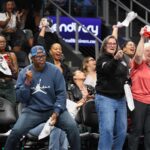 A diverse crowd of passionate basketball fans cheering and waving towels in an arena stands