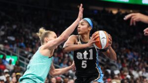 An Atlanta Dream basketball player holding the ball during a WNBA game with a defender closing in