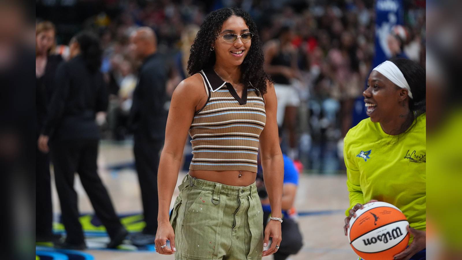 Azzi Fudd standing on a basketball court wearing a striped top and green pants