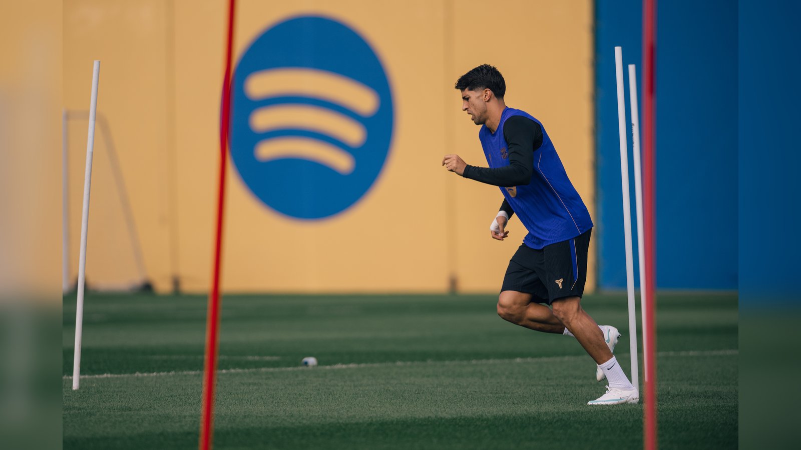 An FC Barcelona player running during a training session with training poles