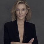 Portrait of actress Cate Blanchett wearing a dark blazer against a grey background