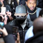 US singer Chris Brown wearing a cap and mask surrounded by cameras and reporters in London