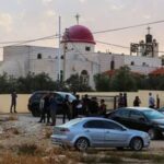 People gathered outside a church with a red dome in Jordan during daylight
