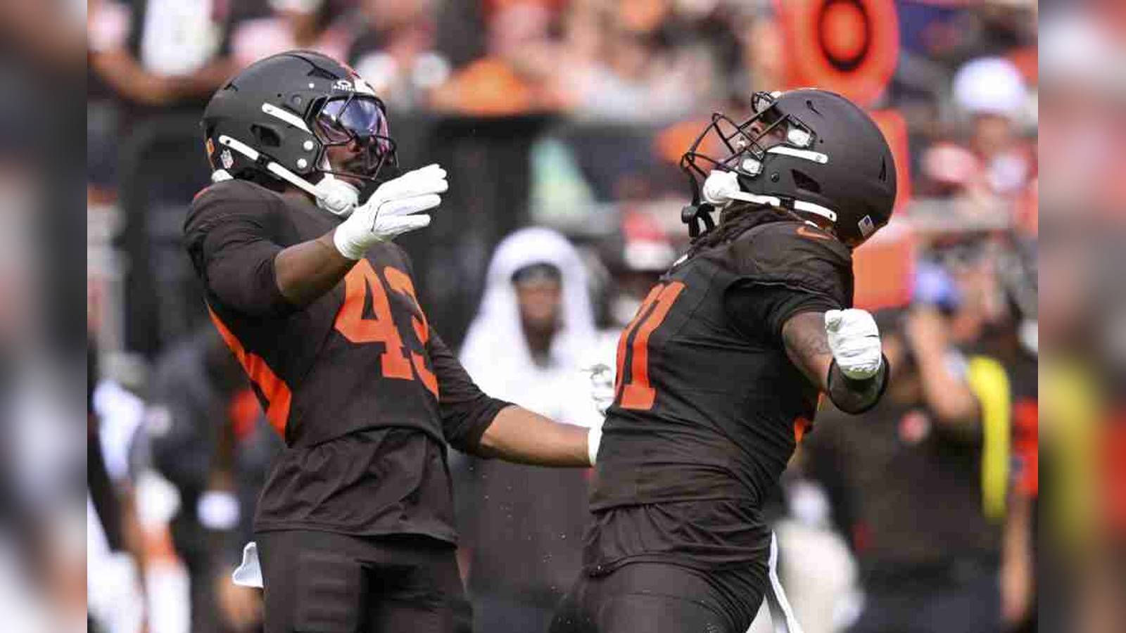 Two Cleveland Browns football players in black uniforms celebrating during a game on the field