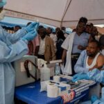 Medical workers in protective gear administering Ebola vaccinations to people in Congo during an out